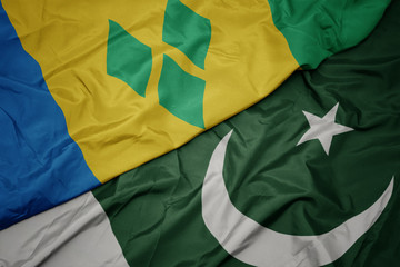 waving colorful flag of pakistan and national flag of saint vincent and the grenadines.