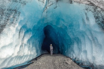 A woman walking into an ice cave in Alaska  - 285487550