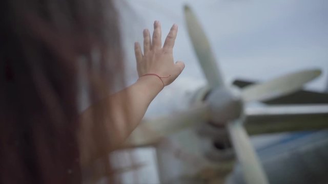 The girl reaching for the propeller of the white plane close-up. The hair is fluttering on the wind. Concept of traveling, aircraft, weekend, flight