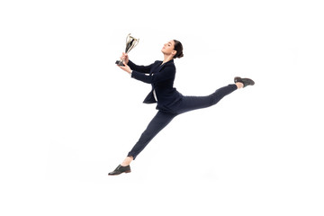 Fototapeta na wymiar happy businesswoman holding trophy cup while jumping in dance isolated on white