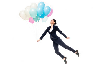 Fototapeta na wymiar happy businesswoman in formal wear levitating with festive balloons isolated on white