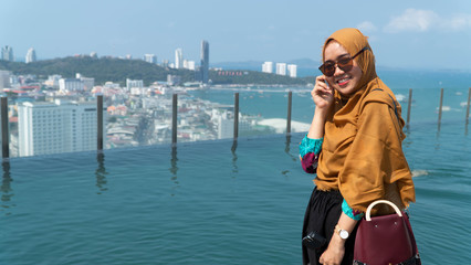 Outdoors lifestyle fashion portrait of pretty muslim woman with hijab walking on the roof. Enjoying summer.