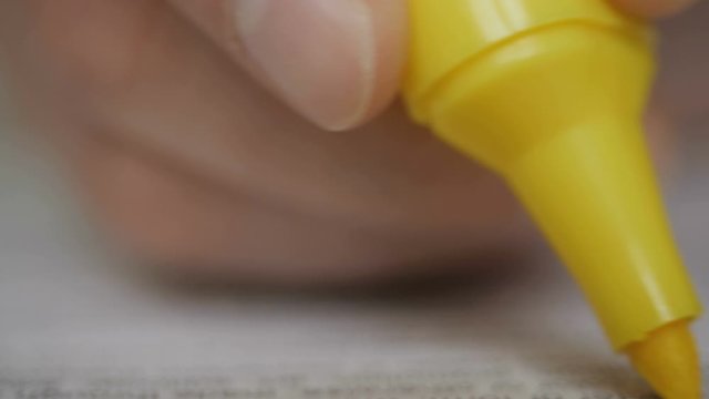 Close up of student hand underlining a document on a desk at home. Highlighter  in man hand  marked text in book, education concept. Closeup. Thumbing pages and highlighting text with marker. UHD 4K.