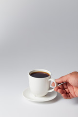 Hand holding a white cup of coffee