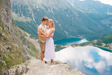 Naklejka premium Happy loving couple standing together at stone in High Tatra national park in Poland with a picturesque landscape on background.