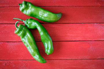 Tasty raw green peppers with red background