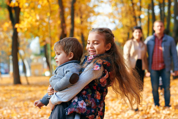 Happy family having holiday in autumn city park. Children and parents posing, smiling, playing and...