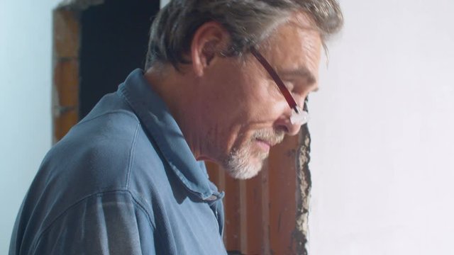 Close up portrait of handsome elderly architect talking to workers in a house under construction.