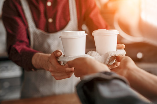 Barista serving coffee in takeaway cups in coffee shop