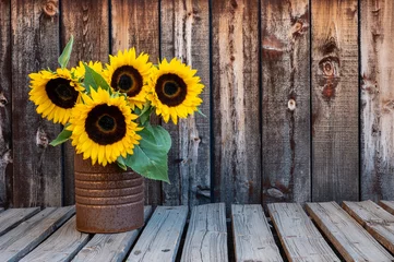 Foto op Aluminium A rusty can filled with a bouquet of sunflowers on a rustic wooden plank table with space for copy. © Mary Lynn Strand
