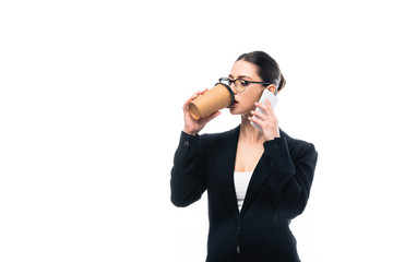 young businesswoman drinking coffee to go while talking on smartphone isolated on white