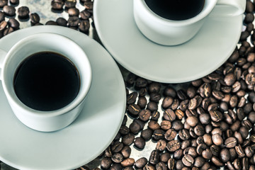 a cup of brewed coffee surrounded by whole unground beans