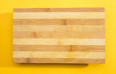 Wooden chopping board on yellow background