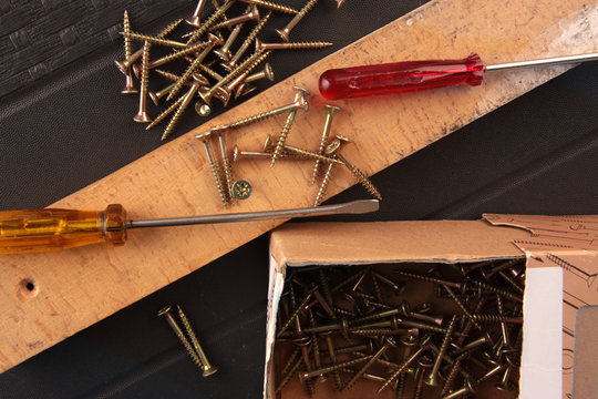 Two screwdriver and a lot of screws on wood