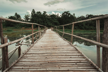 Fototapeta na wymiar Wooden bridge made of bamboo across the water. The concept for the building project.