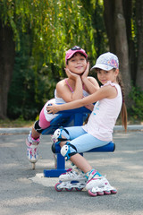 Obraz premium Girls on the playground. Two girls in roller skates sit on a sports field simulator