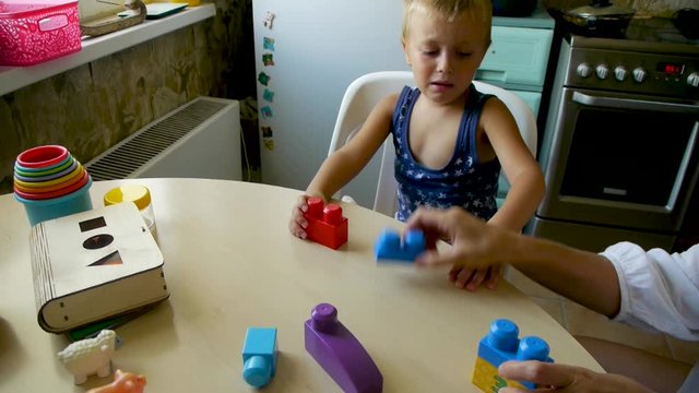 autistic child fulfills a task - collects a constructor following the example of an assistant