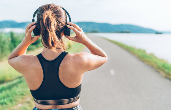 Young teenager girl adjusting  wireless headphones before starting jogging and listening to music