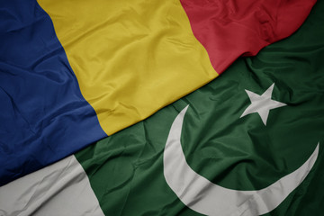 waving colorful flag of pakistan and national flag of romania.