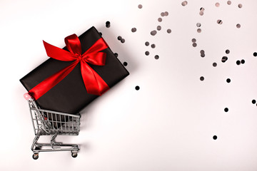 Gift box with red bow in a metal shopping basket with place for text.