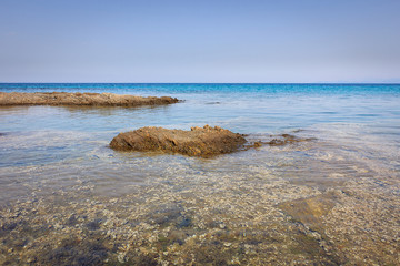 Calm translucent turquoise sea, beautiful rocky reef and distant horizon