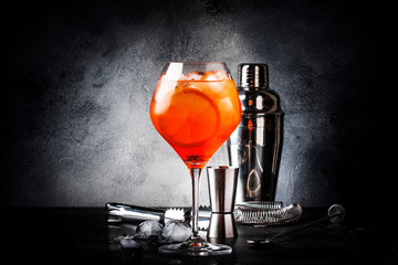 Aperol spritz cocktail in big wine glass with orange and ice, summer alcoholic cold drink, dark bar...