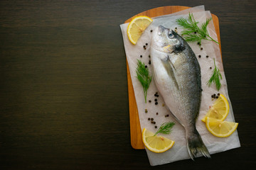 Dorado fish on a cutting board with salt and spices lemon slices. Food photo.