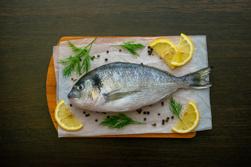 Dorado fish on a cutting board with salt and spices lemon slices. Food photo.