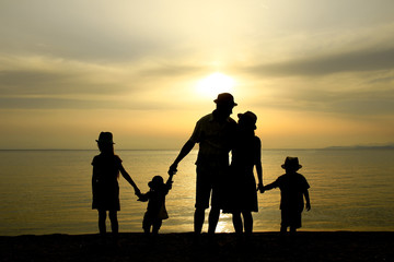 Fototapeta na wymiar family silhouette at sunset by the sea