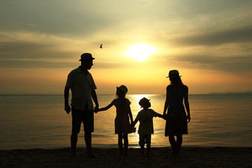 family silhouette at sunset by the sea