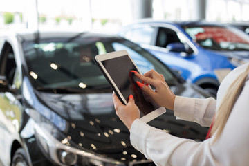 Woman dealer using digital tablet at dealer showroom. Touching screen digital tablet. Modern working process.