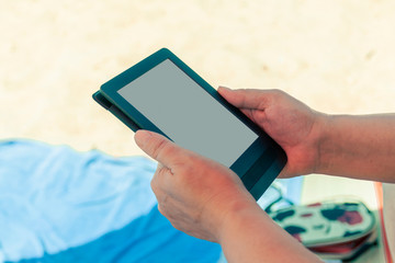 Woman on the beach reads an e-book.