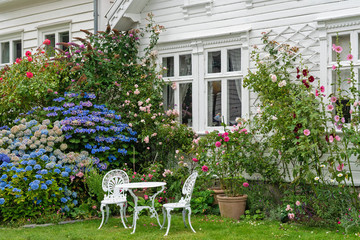 Fototapeta na wymiar Garden with table and chairs near traditional Norwegian white wooden house, Stavanger, Norway.