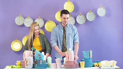 Cheerful happy family enjoying working in the kitchen. Happiness, feeling, emotion concept. Hardworking wife and husband standing behind the table full of dirty used cutlery