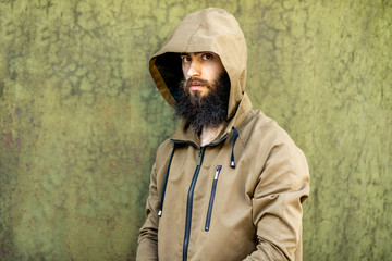 Portrait of a mysterious and weird man wearing hoodie coat on the green rusty wall background
