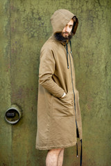Portrait of a mysterious and weird man wearing hoodie coat on the green rusty wall background