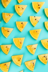 Pattern of slices of fresh yellow watermelon on a blue background. View from above. Free space