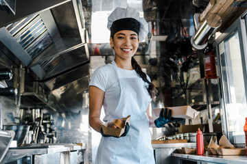 happy asian chef holding carton plates in food truck