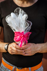 Man holding a bouquet made of plastic garbage, close-up. Concept of non-recyclable plastic pollution