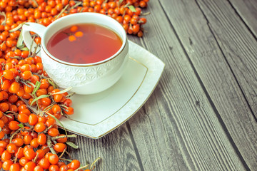 A Cup of hot tea  and sea buckthorn berries on a dark wooden background. Autumn concept. Top view, flat lay composition. Copy space for text.