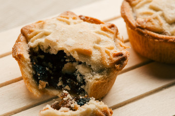 Blueberry mince pie with broken off piece on wooden board