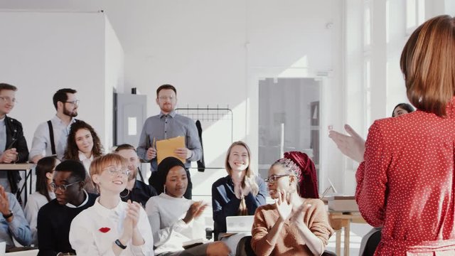 Happy multiethnic team applause to female coach leading conference seminar at modern trendy office slow motion RED EPIC.