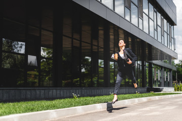 happy businesswoman levitating while holding briefcase and coffee to go