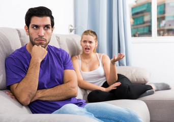 Frustrated guy on couch with dissatisfied girlfriend