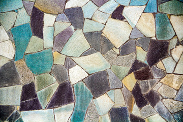 Decorative texture of concrete fencing from stones of different sizes, shapes and colors in the form of a mosaic.