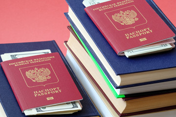two foreign passports of Russians are on different stacks of books