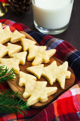 Christmas homemade cookies, glass of milk, cinnamon and festive decor on a wooden table. Holiday and cooking concept. Christmas and new year postcard.
