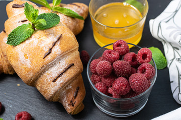 Tasty French breakfast with croissants, honey, mint leaves fruits on black background top view. Tasty homemade breakfast concept.