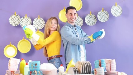 Positive awesome young man and woman looking at each other while wiping plates. Happiness, family working in kitchen