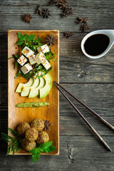 Tofu und Falafel mit frischem Gemüse, Avocado und Gewürzen auf einem Teller und einem Holztisch, Ansicht von oben, orientalische Art